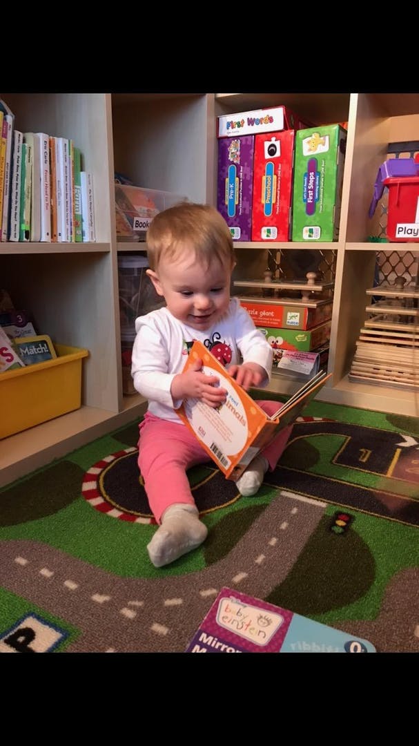 Child sitting on a rug and holding an open book