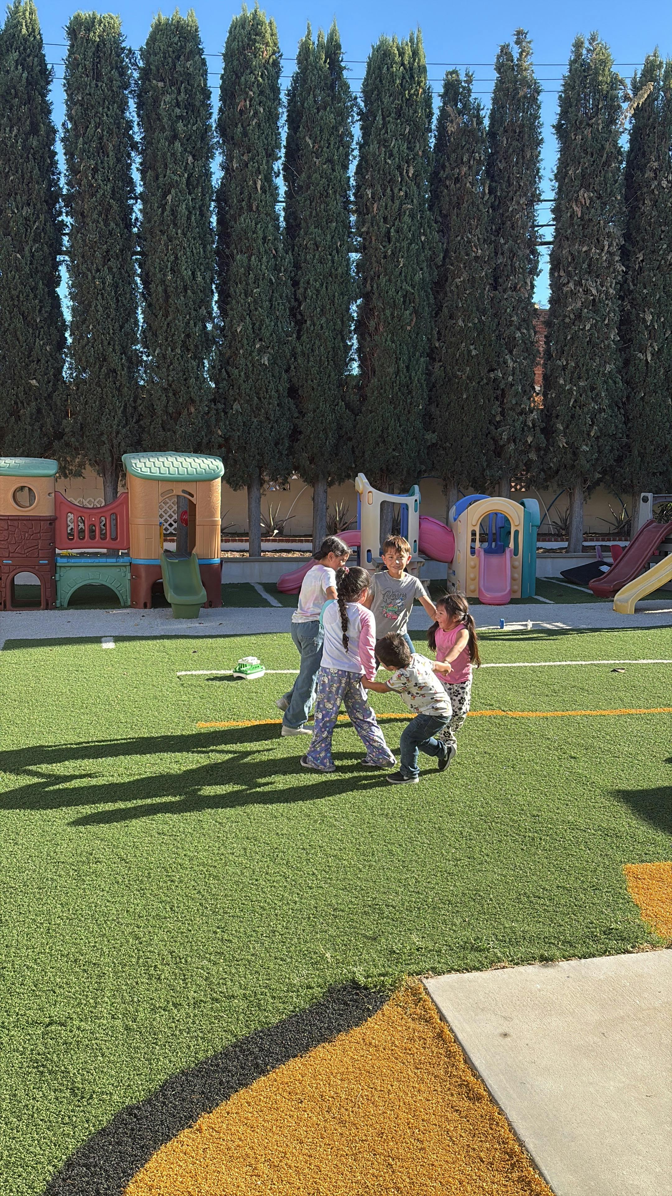 Group of children playing on a green turf playground