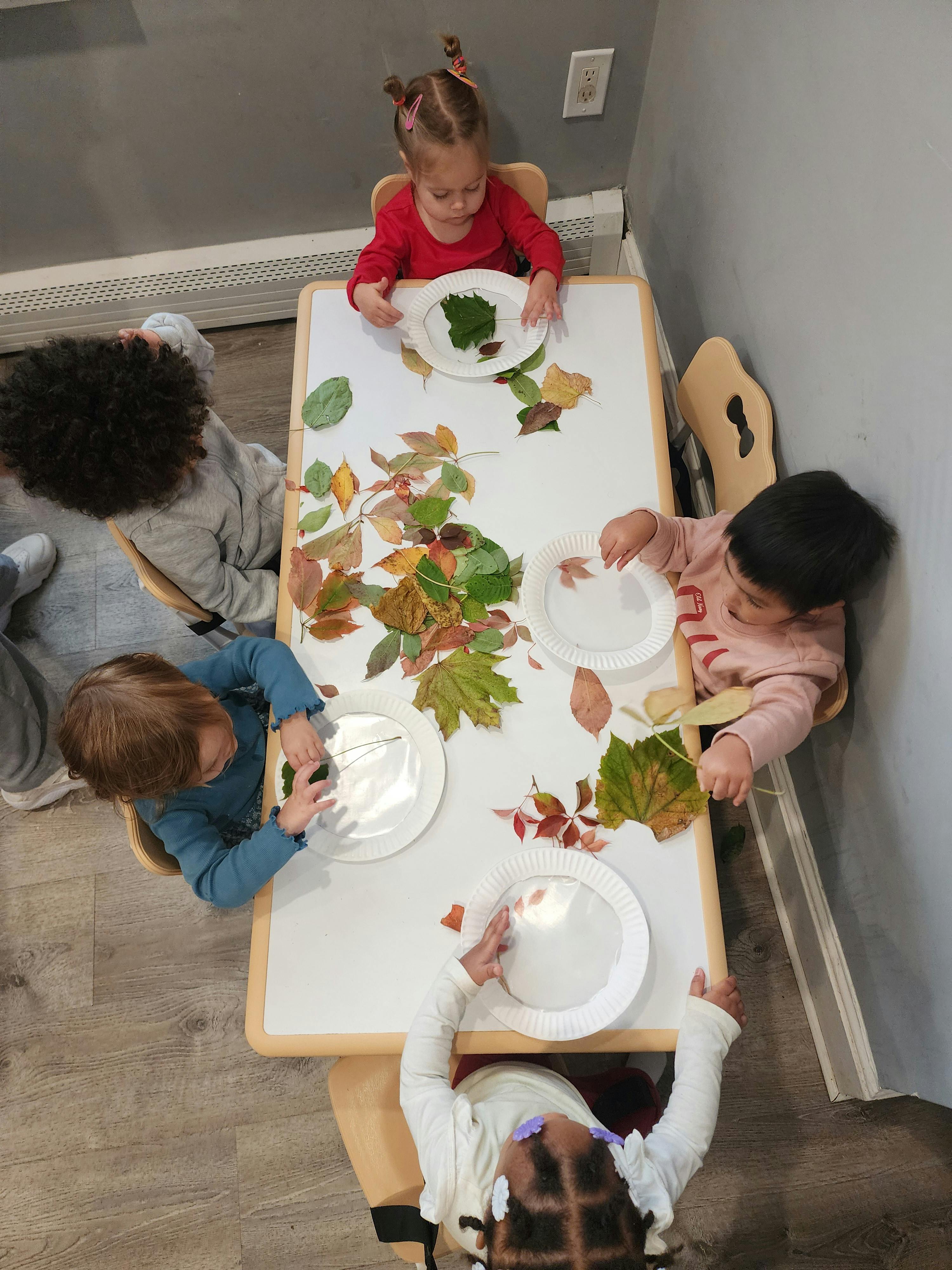 Children at a table with leaves and paper plates