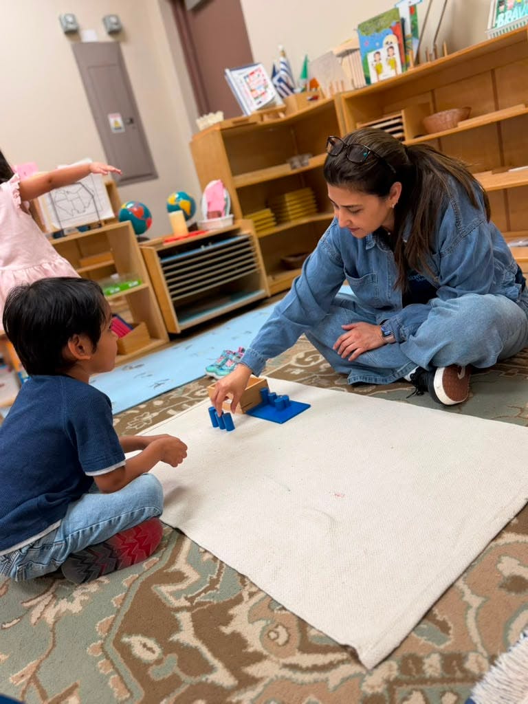 Adult and child sitting on a rug interacting with educational blocks
