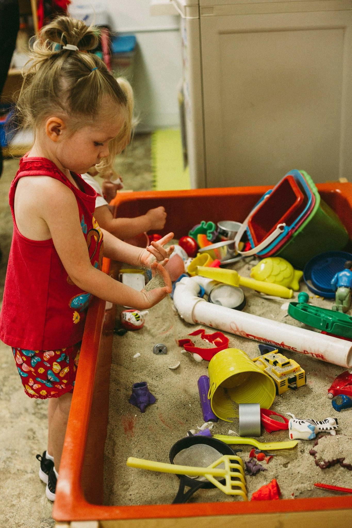 Child playing in a sand table with toys