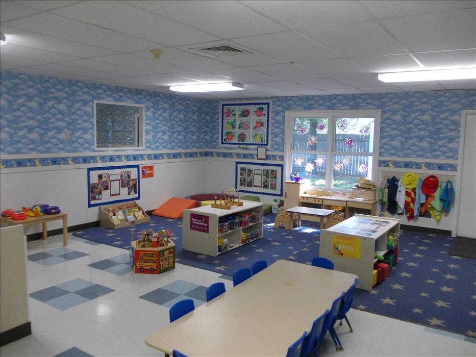 Childcare classroom with tables, chairs, toys, and blue decor