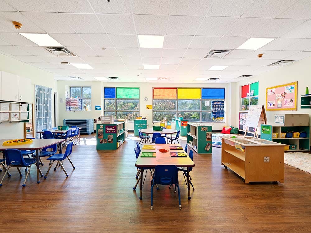 Empty classroom with tables and chairs, colorful window blinds