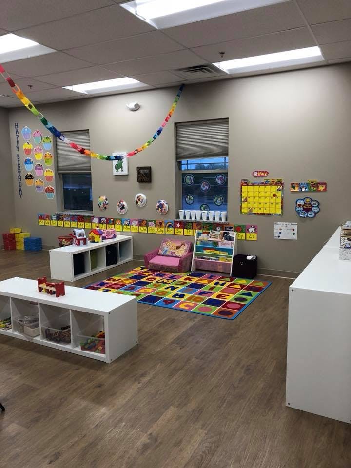 Empty classroom with colorful rug, shelves, and decorations