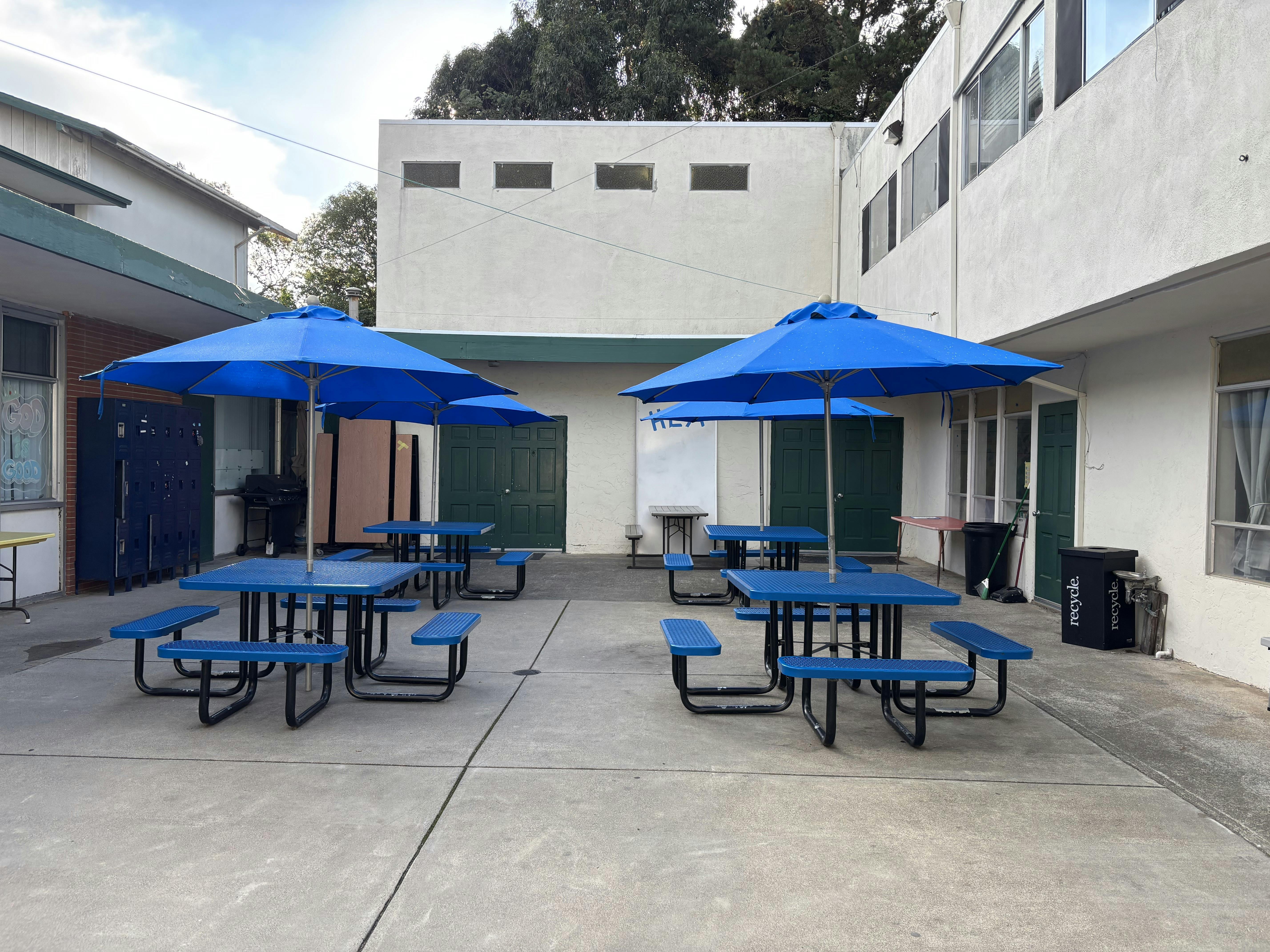 Outdoor courtyard with blue picnic tables and umbrellas