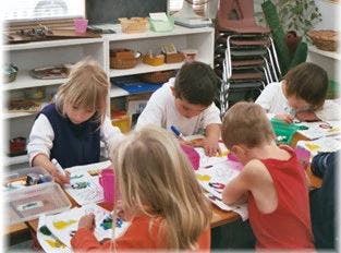 Children drawing and coloring at a table in a classroom