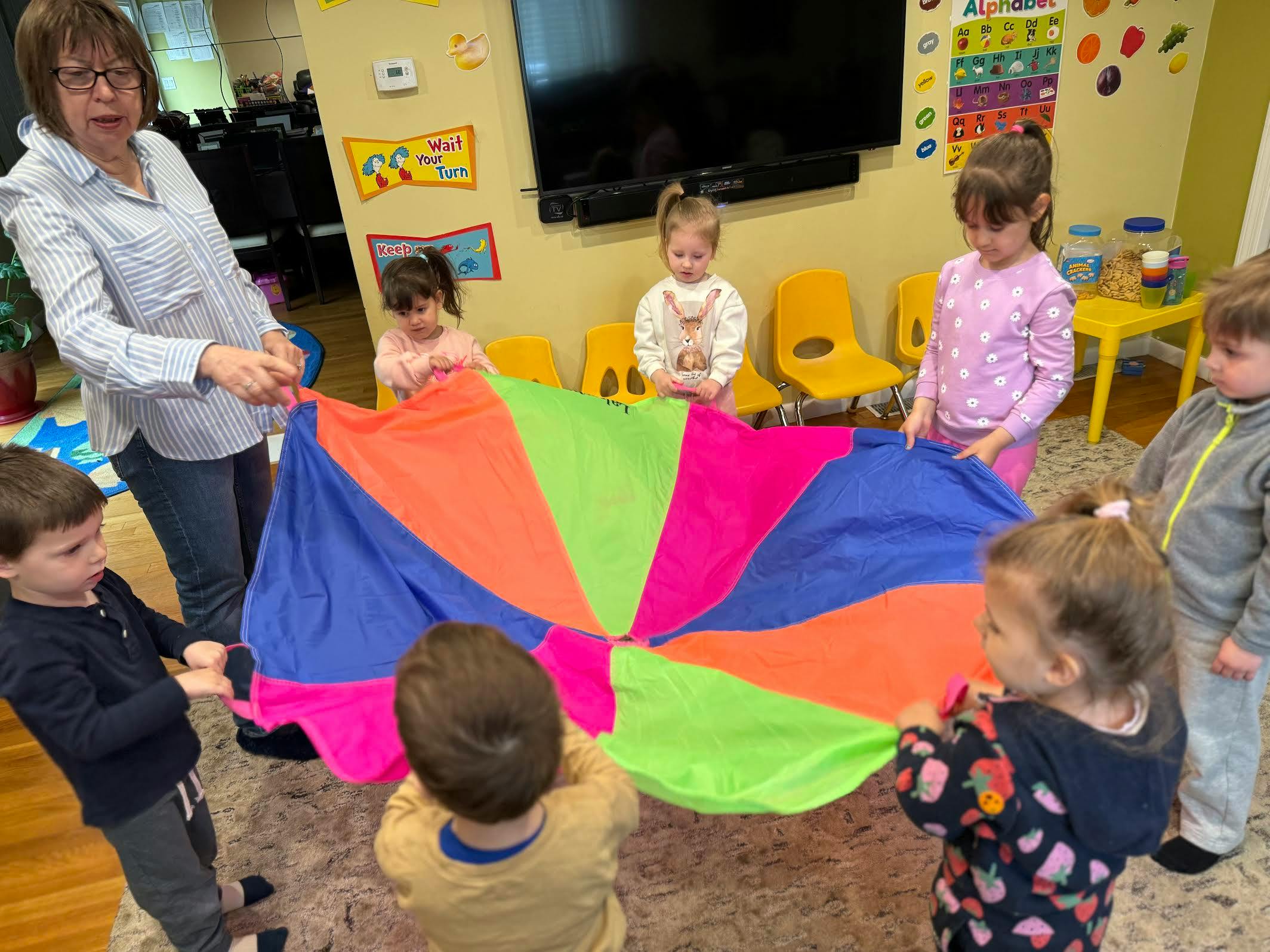 Adult and children playing with a colorful parachute