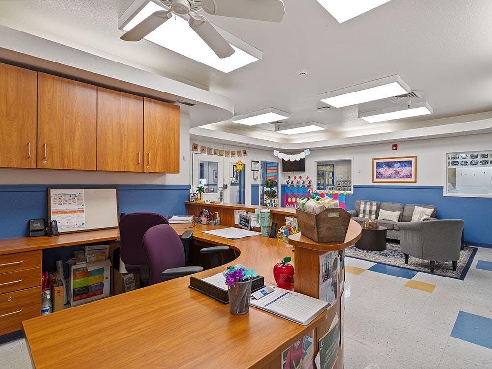 Reception desk with office chairs, and a waiting area with a sofa and armchairs