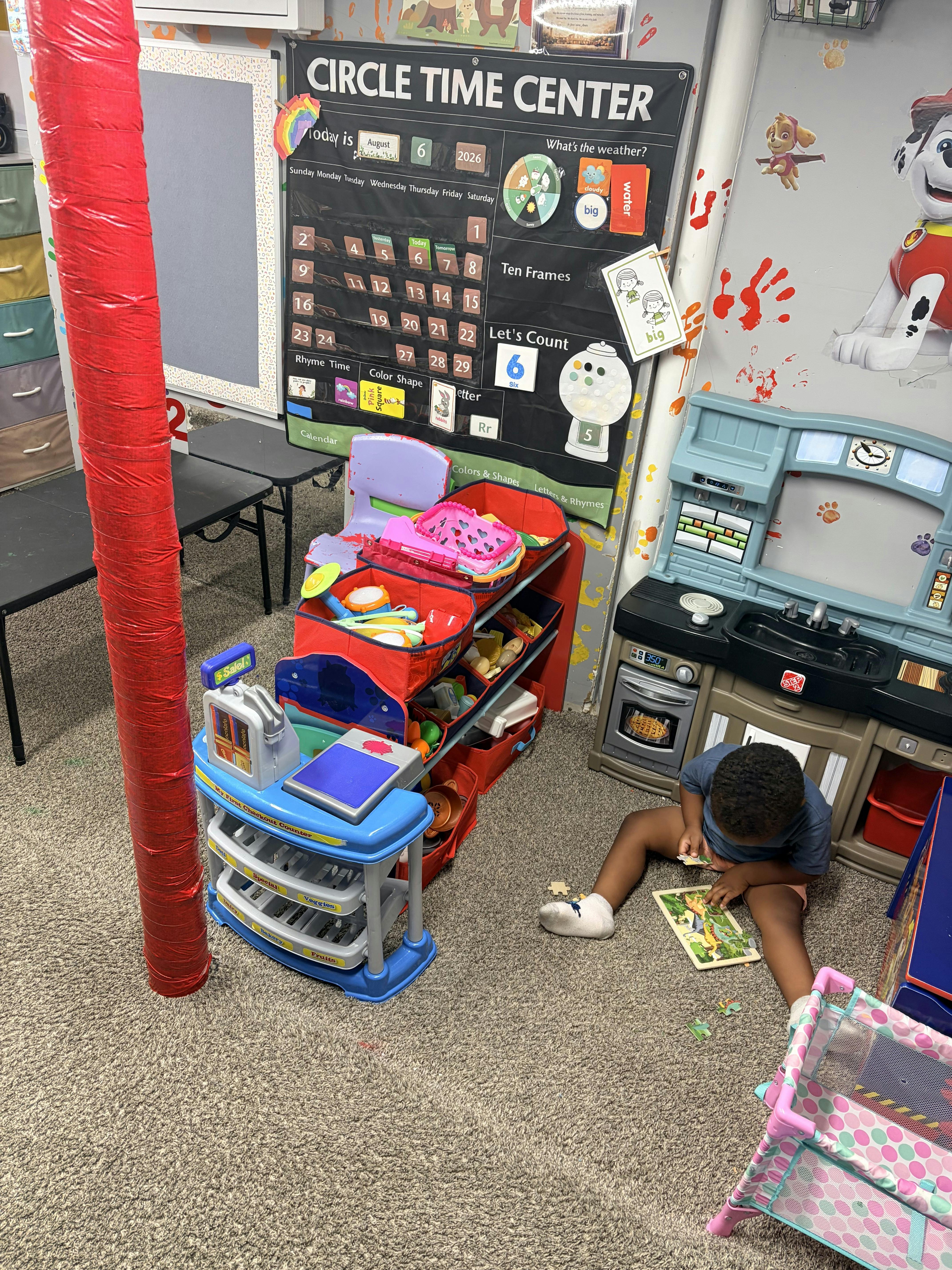 Child sitting on a carpeted floor playing with a puzzle in a classroom