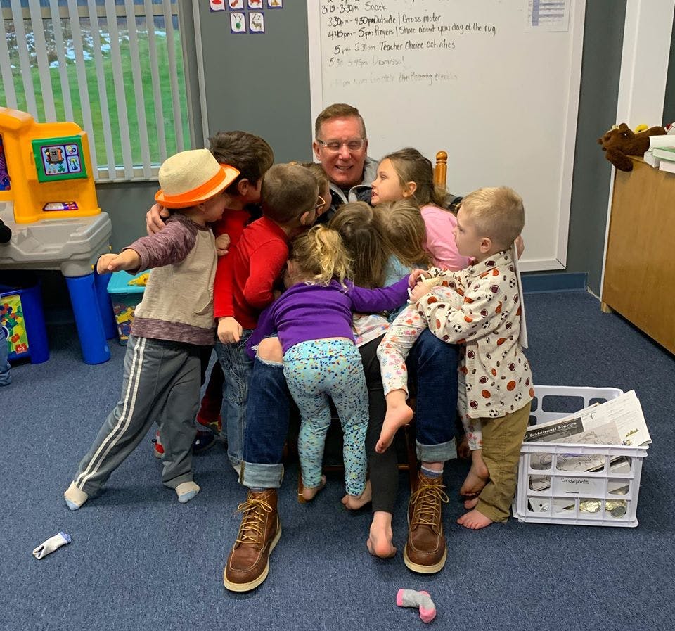 Adult person sitting on floor surrounded by multiple children