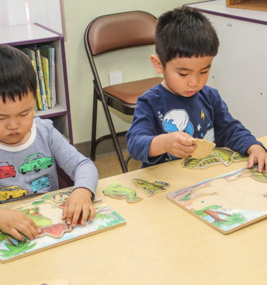 Two children playing with puzzles at a table