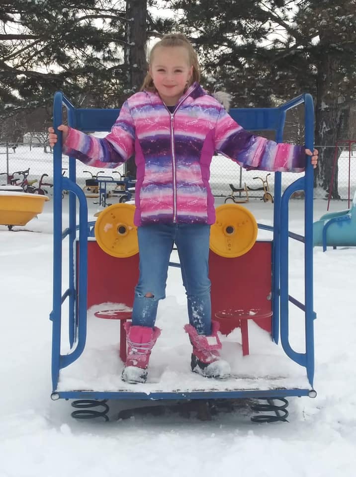 Child standing on a playground ride in the snow