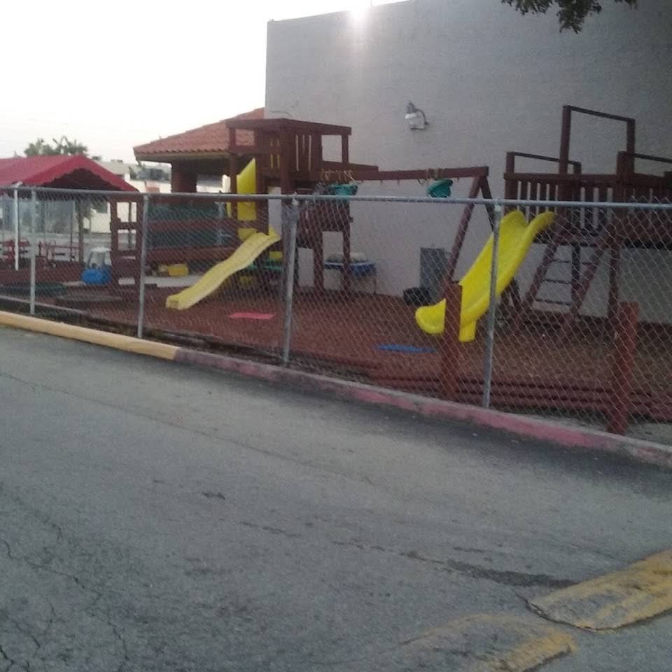 Playground with yellow slides and wooden structures behind a chain-link fence