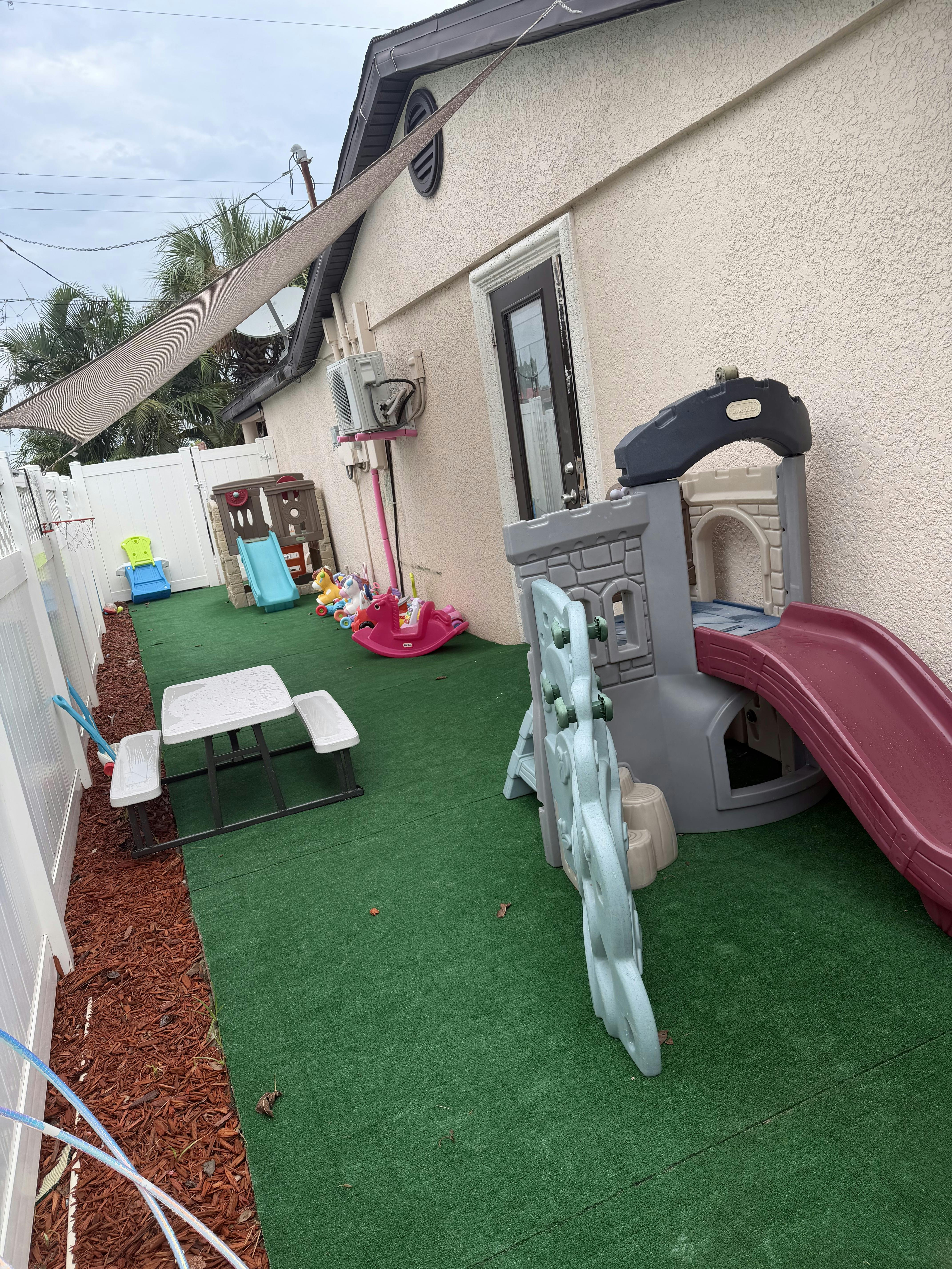 Plastic playground equipment and a small table on artificial turf in a yard