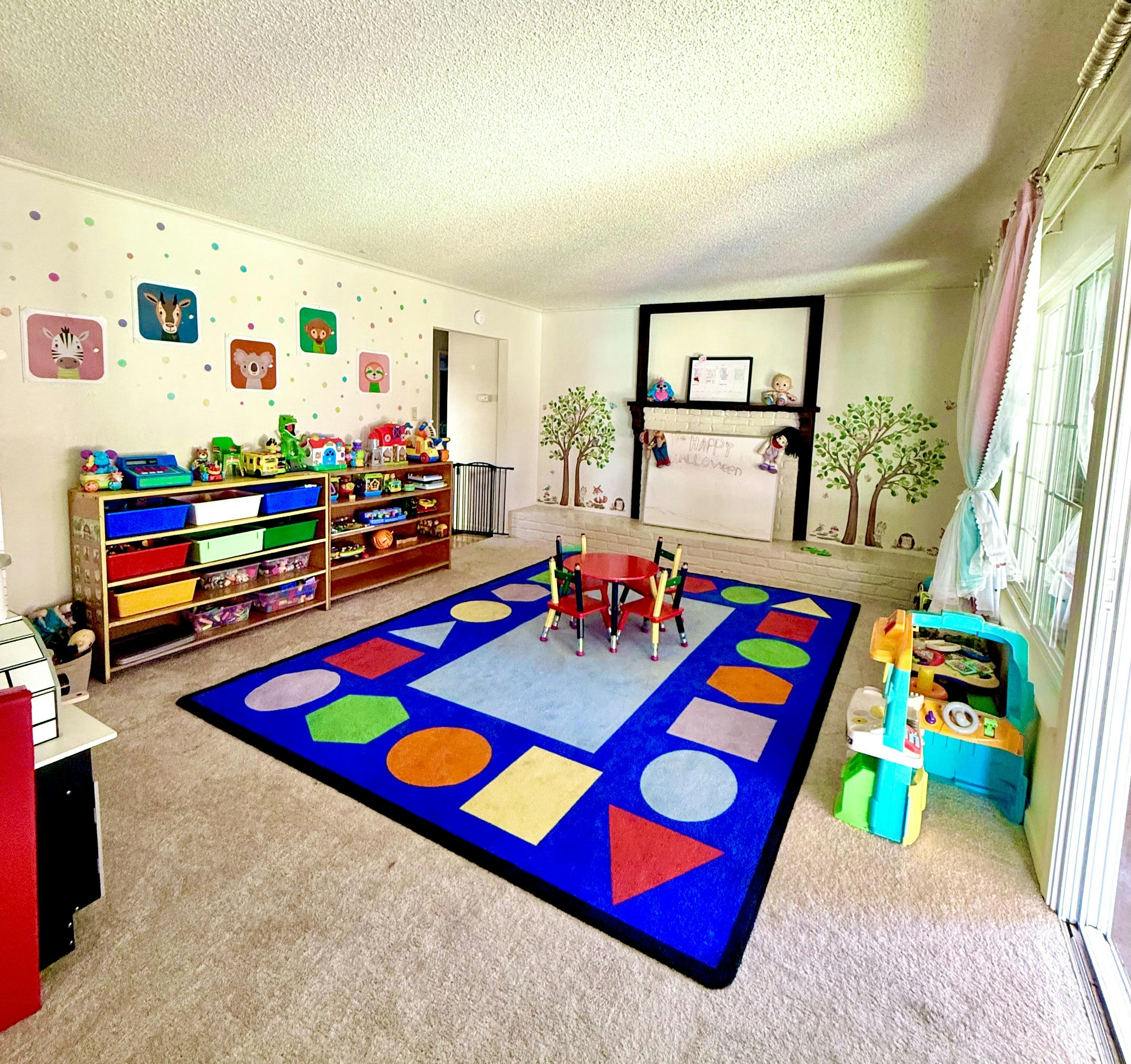 Playroom with colorful shape rug, small table and toy storage shelves