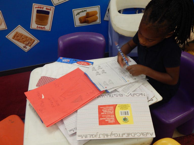 Child writing on paper at a table