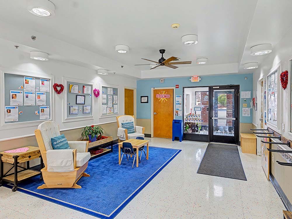 Lounge area with two rocking chairs, small children's table, and bulletin boards