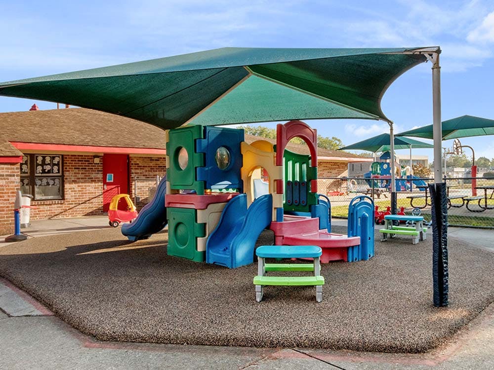 Colorful playground structure with slides under a green shade canopy
