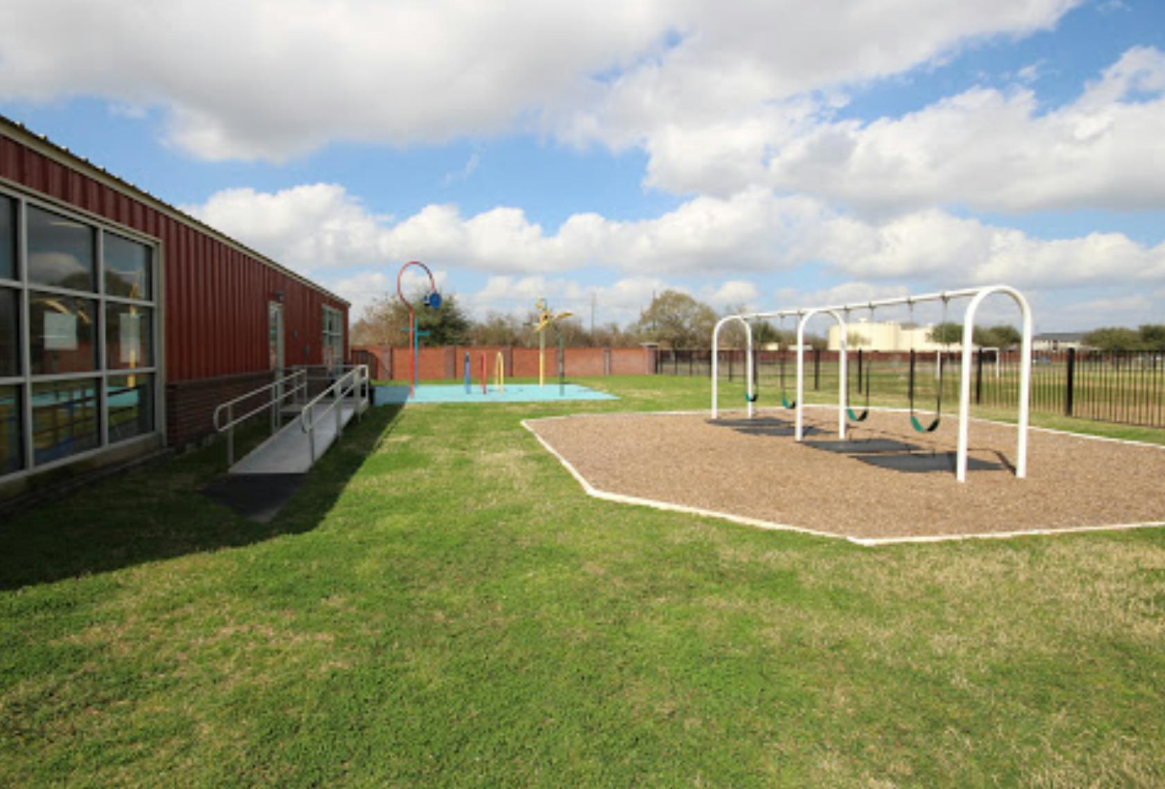 Playground with swings and a building with a ramp