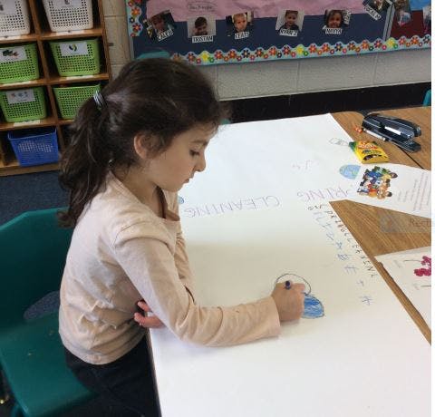 Child drawing on a large white paper at a table