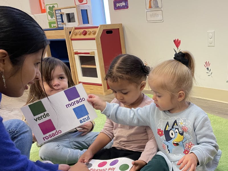 Adult and three children looking at a color chart with Spanish words