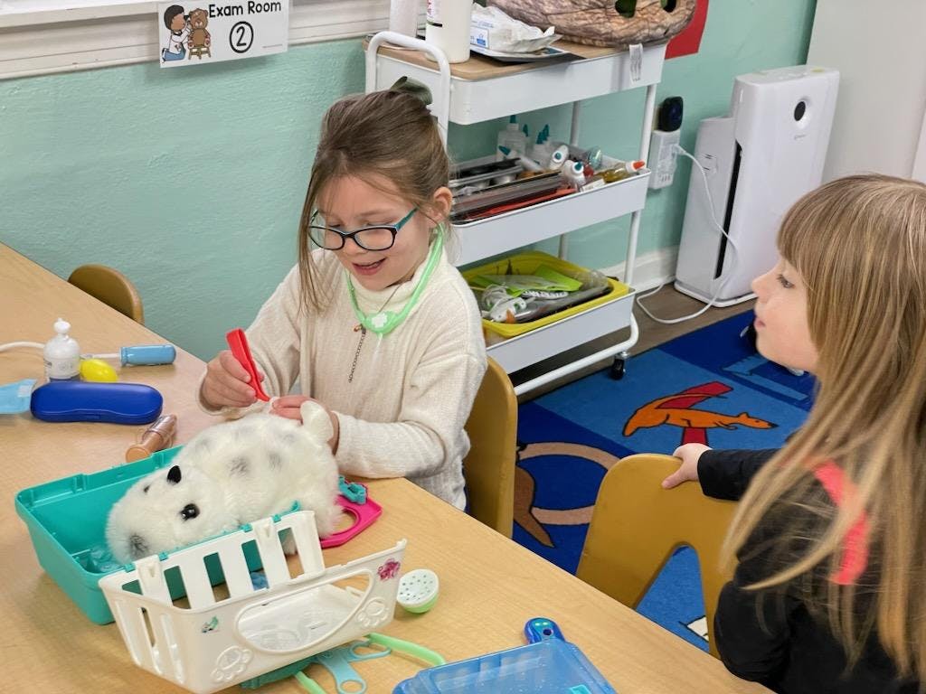 Child playing with a toy animal and medical kit at a table