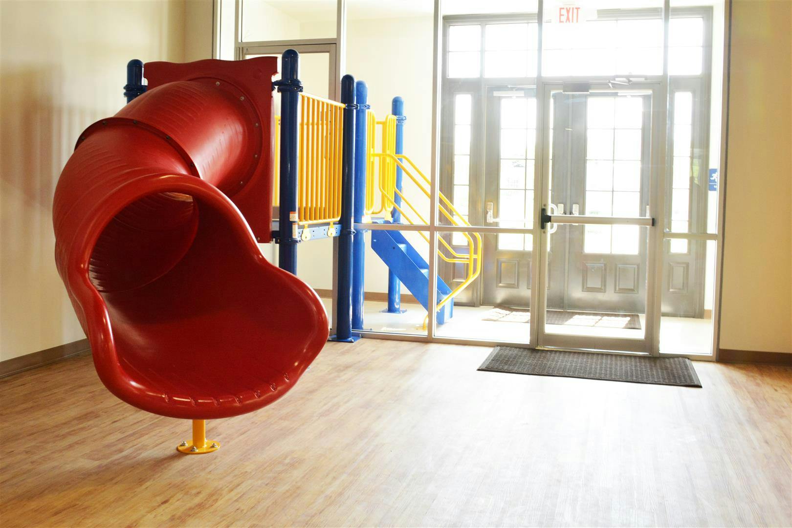 Indoor playground with red slide and blue and yellow climbing structure