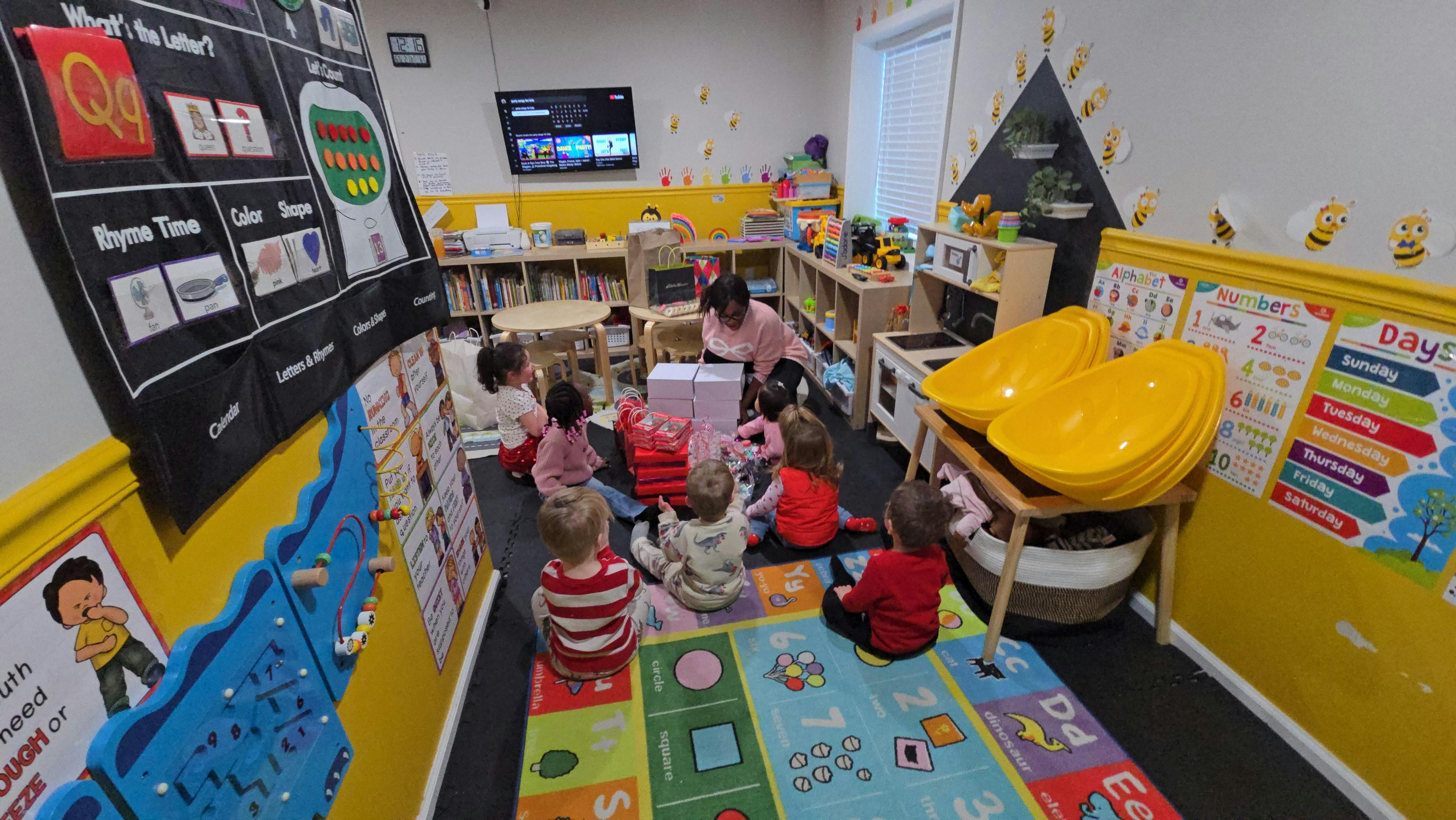 adult and children sitting on a rug in a classroom