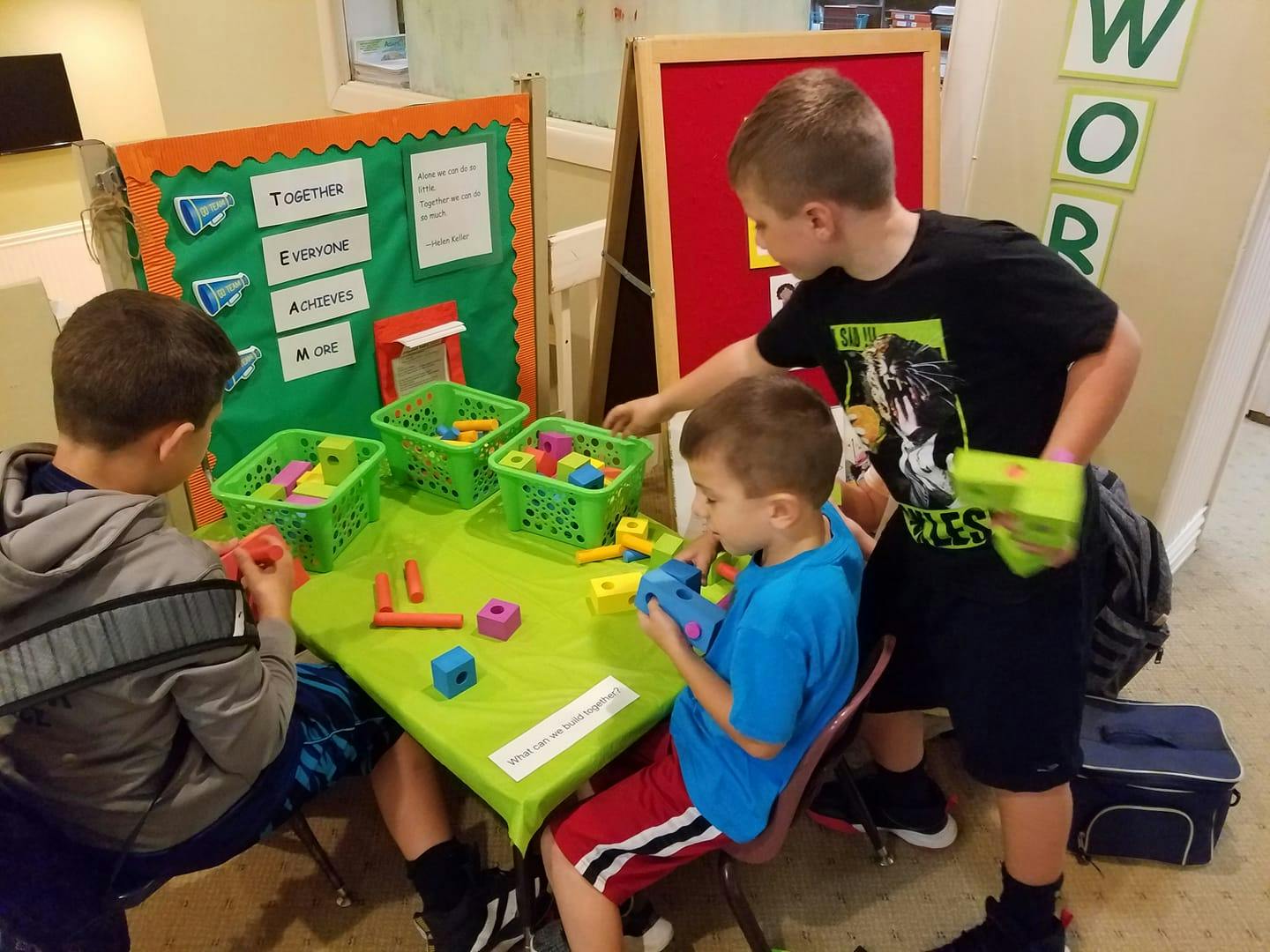 Three children playing with colorful blocks at a table