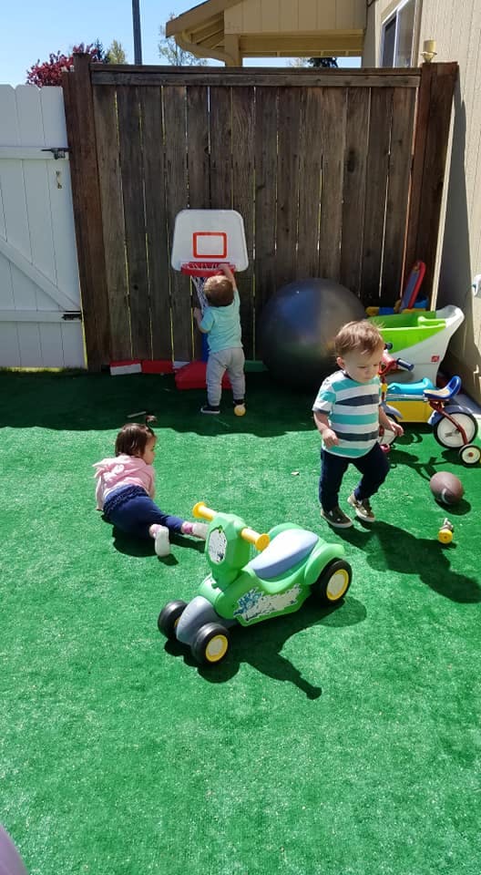 Three children playing with toys on green turf