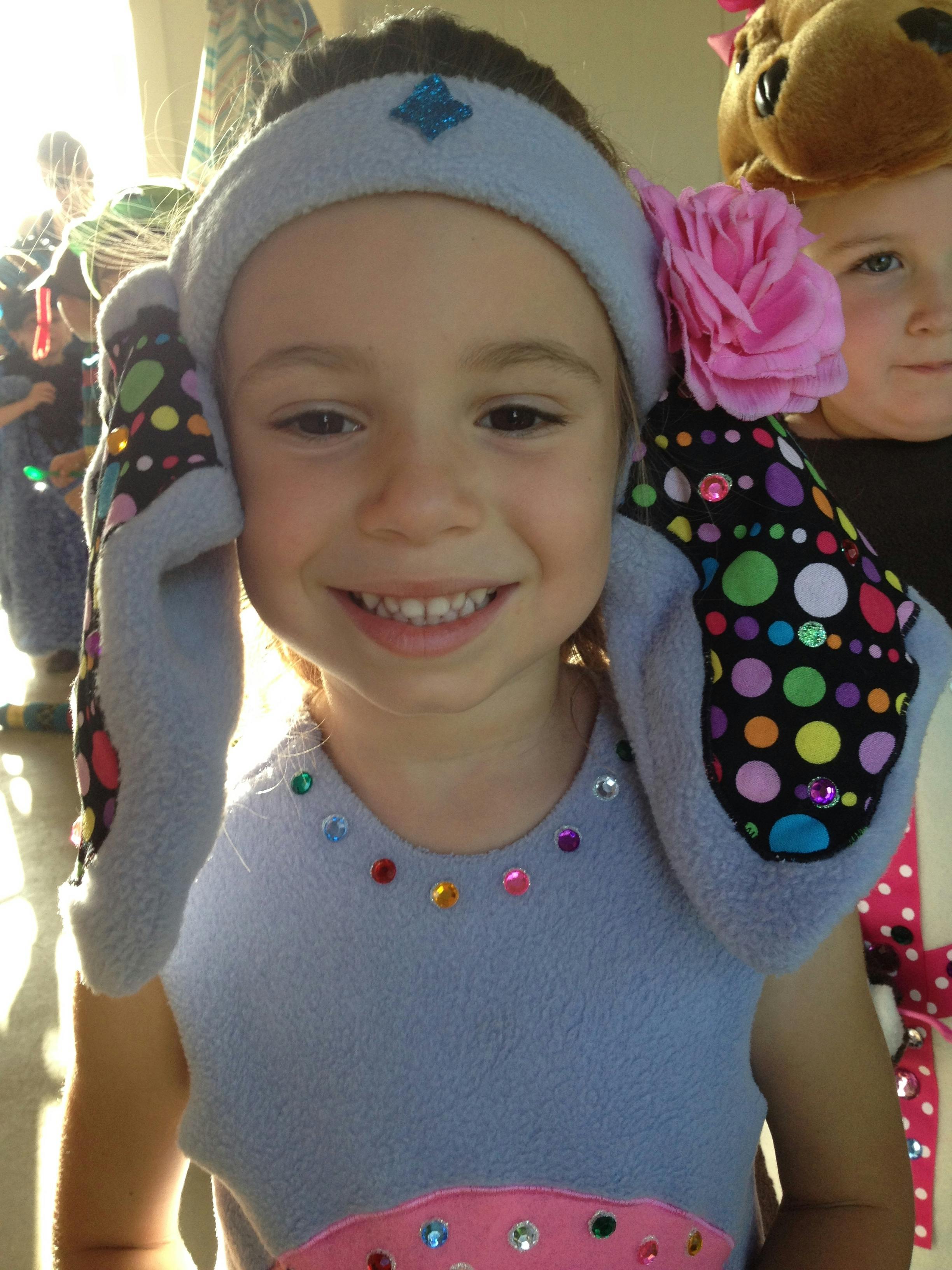 Child wearing a headband with polka dot ears and a pink flower