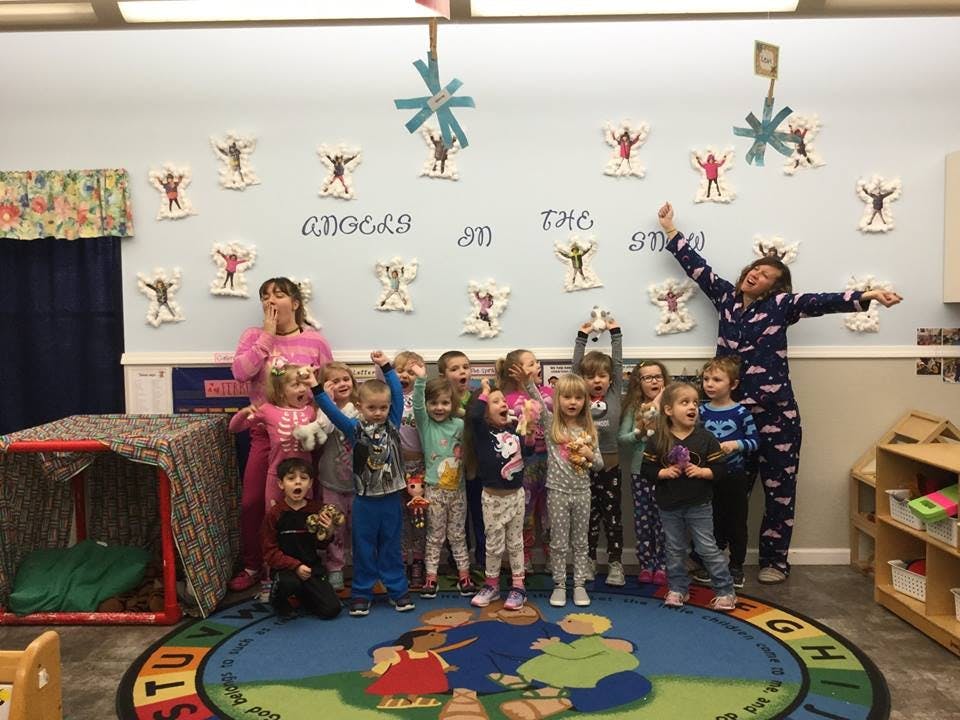 Two adults and multiple children posing in a classroom