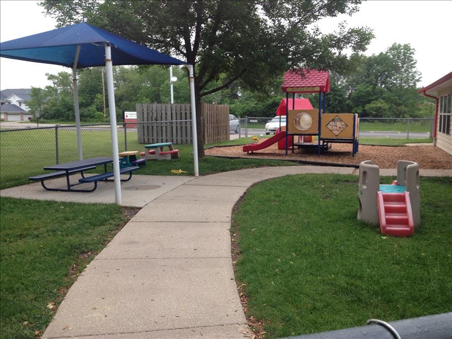 Playground with swings, slides, a small play structure, and picnic tables under a shade