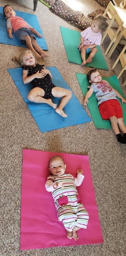 Five children lying on yoga mats on the floor