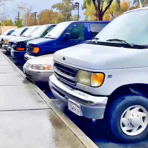 Row of parked vehicles, including vans and cars