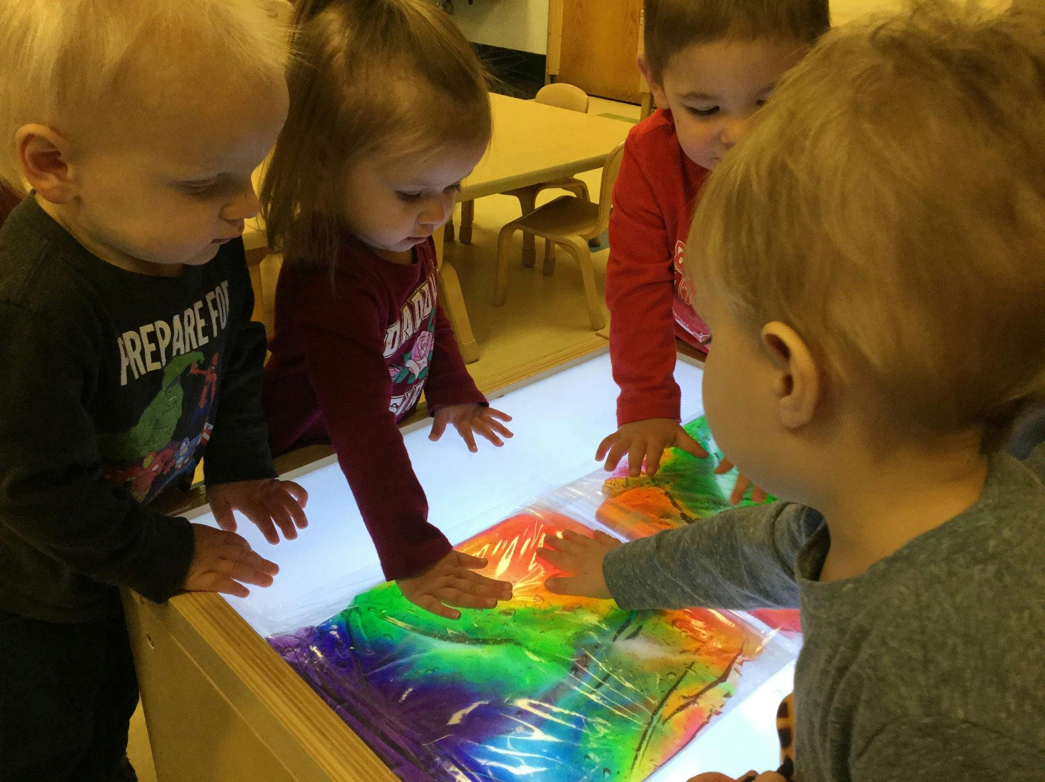 Children playing with colorful sensory bags on a light table