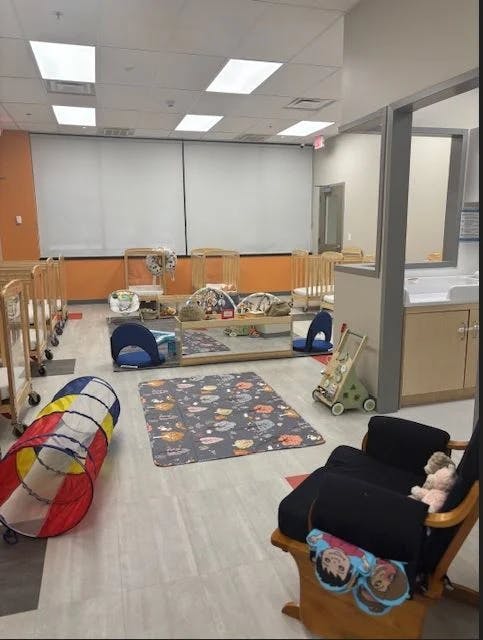 Daycare room with cribs, play mats, and a rocking chair