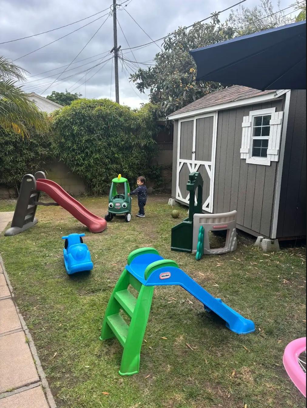 Child standing in a backyard with outdoor play equipment