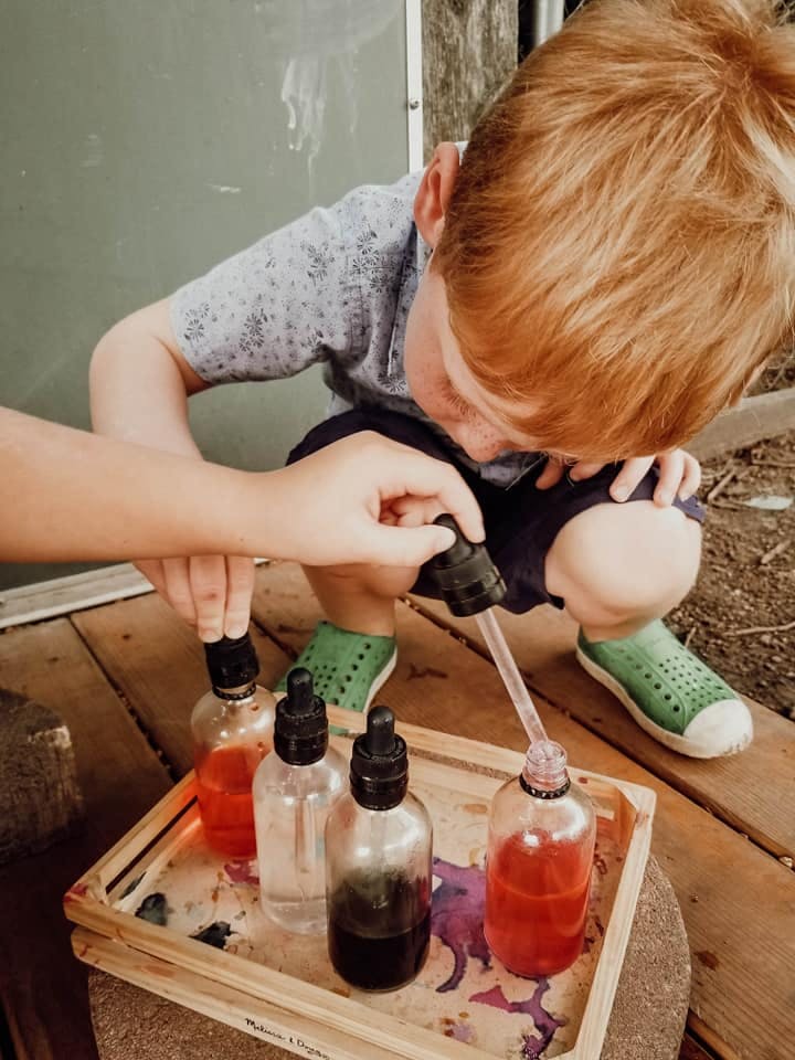 Child and adult hands using droppers with bottles of colored liquid