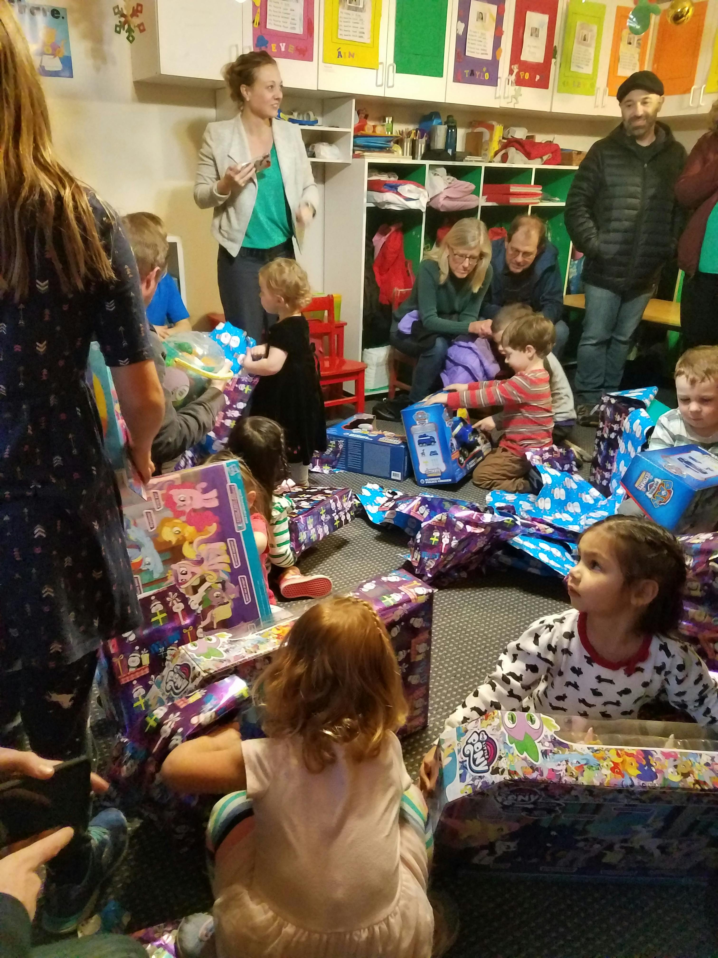 Adults and children opening gifts in a room