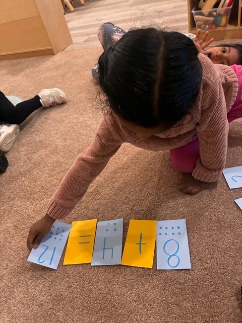 Child on floor arranging number cards