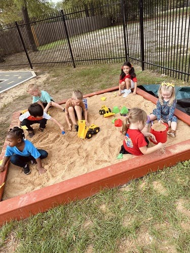 Children playing in a sandbox with toys