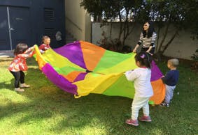 Adult and children playing with a colorful parachute outdoors