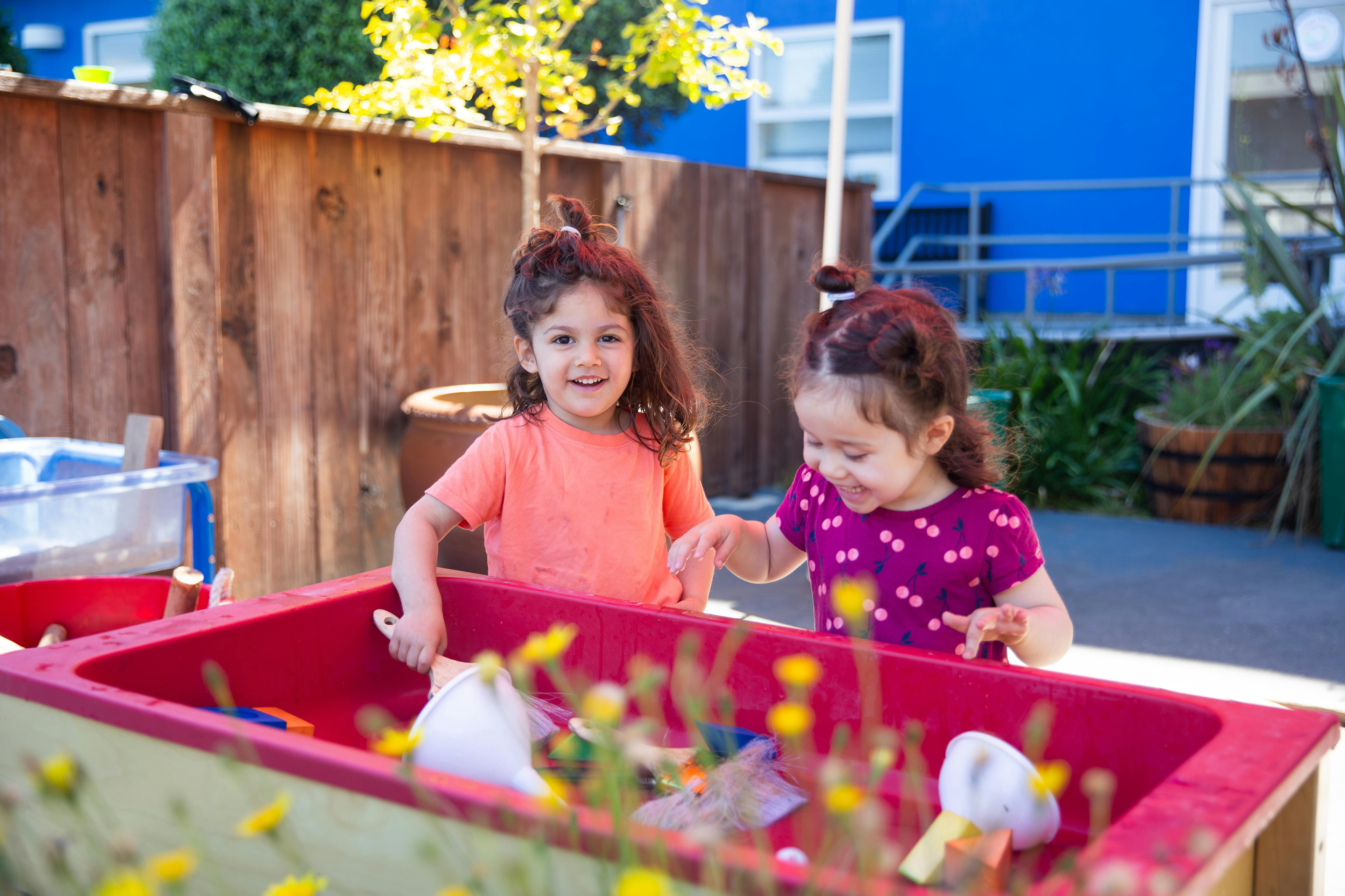 Two children playing with a sensory table outdoors