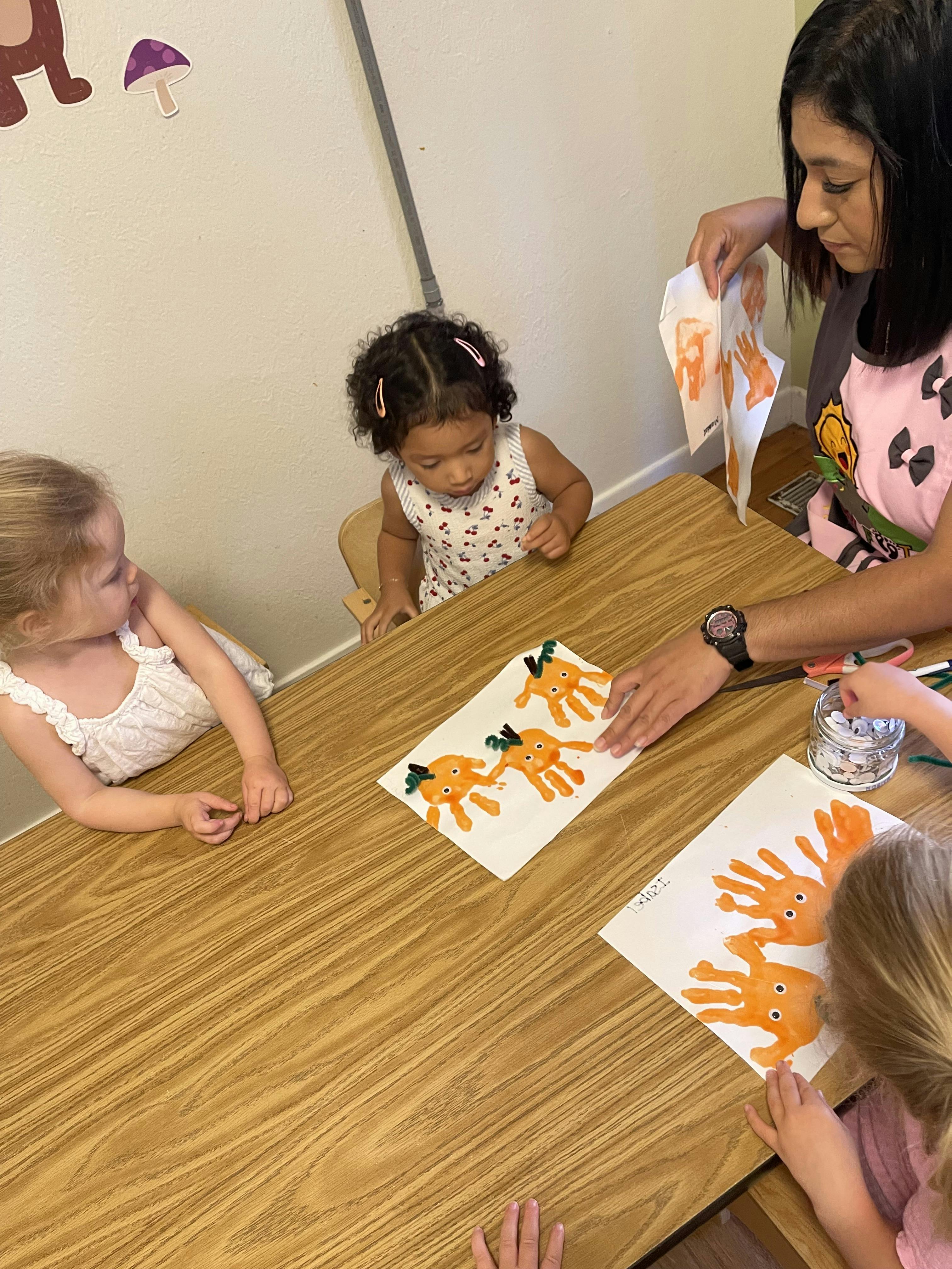 Adult and children crafting handprint carrot art at a table
