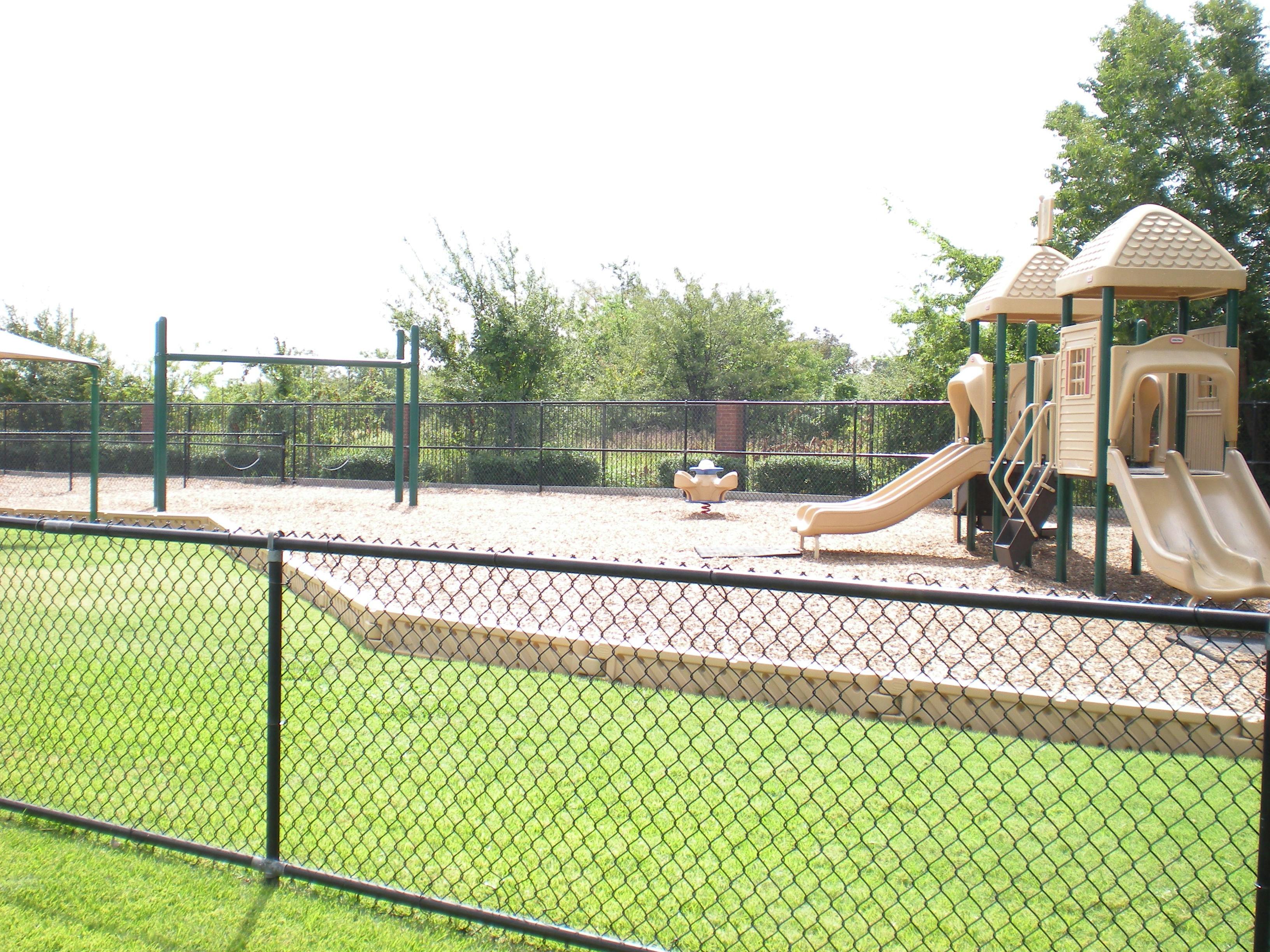 Playground with slides, swings, and a fence