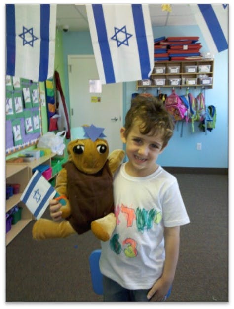 Child holding a stuffed animal that is holding a small flag
