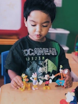 Child playing with toy figures on a table