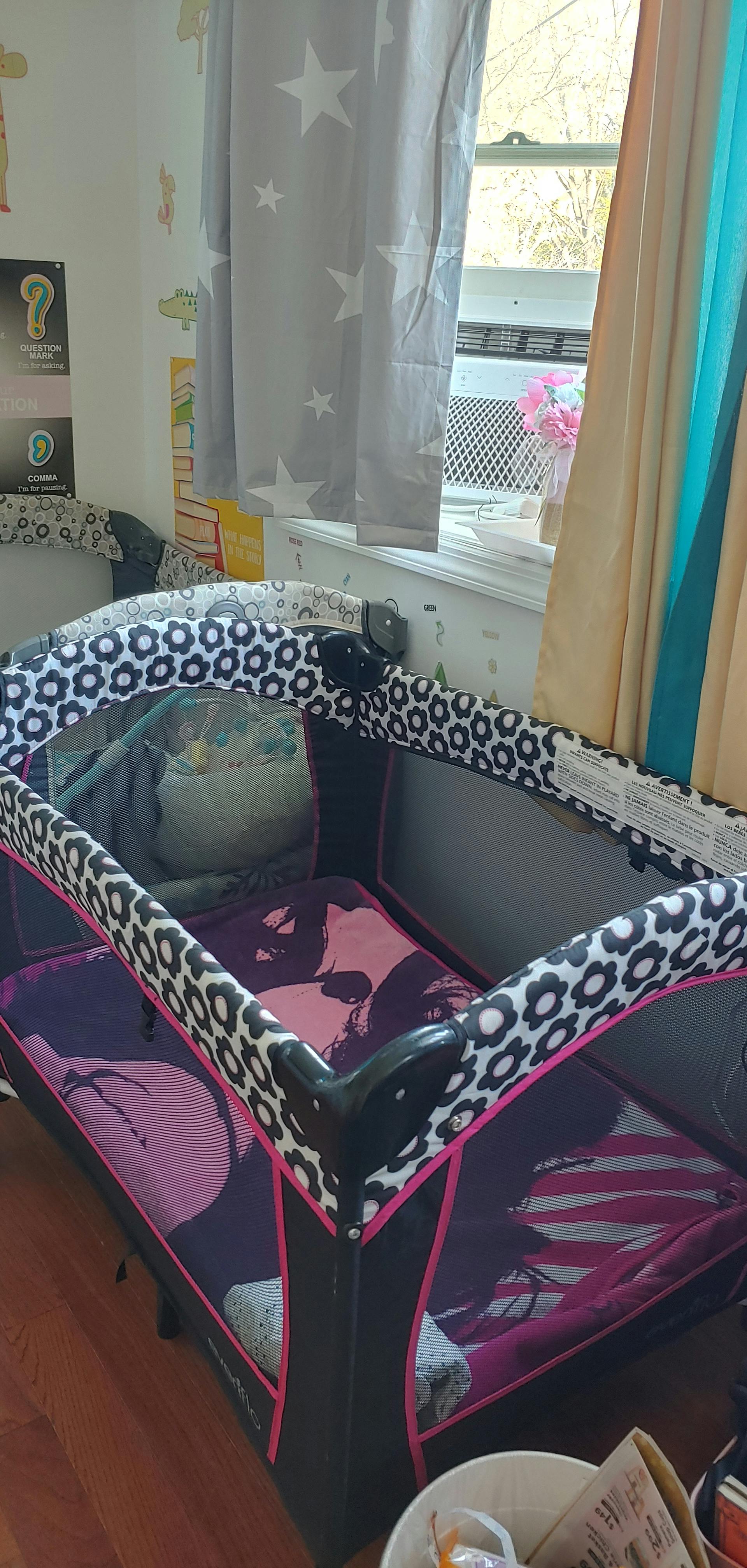 Playard with black and white patterned top rail and purple bedding
