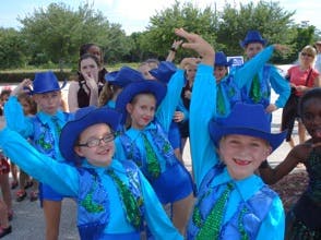 Children in blue costumes and hats posing with arms raised